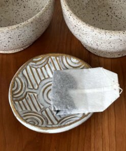 Handmade Pottery Bowl with a interlocking circular stamped pattern being used to hold a tea bag