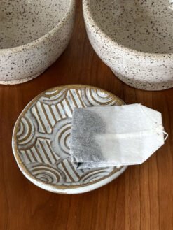 Handmade Pottery Bowl with a interlocking circular stamped pattern being used to hold a tea bag